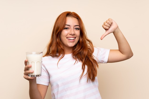 Adolescente rousse tenant un verre de lait fière et satisfaite