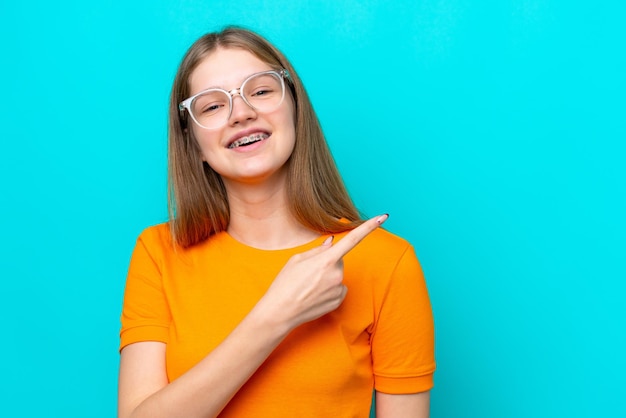 Adolescente russe isolée sur fond bleu avec des lunettes et un côté pointant