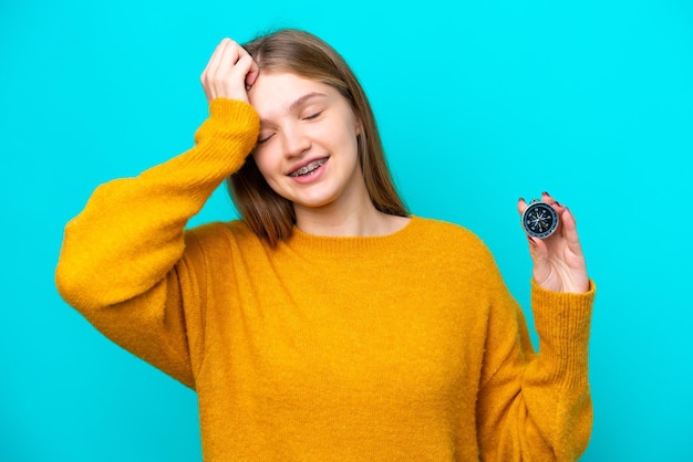 Une adolescente russe tenant une boussole isolée sur fond bleu a réalisé quelque chose et a l'intention de trouver la solution