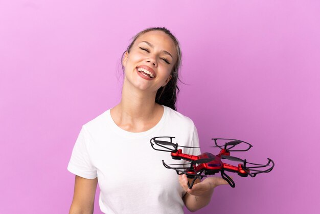 Adolescente russe tenant un drone isolé sur fond violet en riant