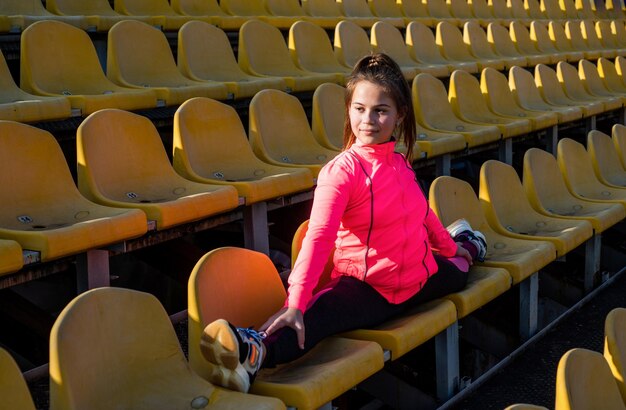 Une adolescente s'assoit dans une gymnaste de tribune de stade en plein air