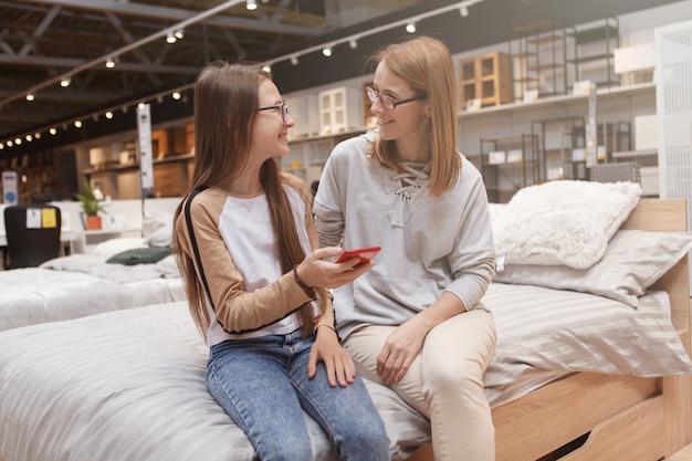 Adolescente et sa mère parlant tout en utilisant un téléphone intelligent ensemble