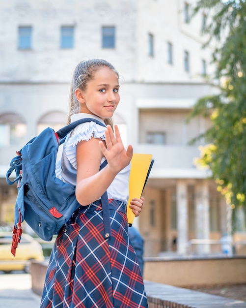 Une adolescente avec un sac à dos et un dossier va à l'école