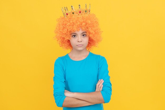 Une adolescente sérieuse en perruque de clown fantaisie porte une couronne de reine, égocentrique.