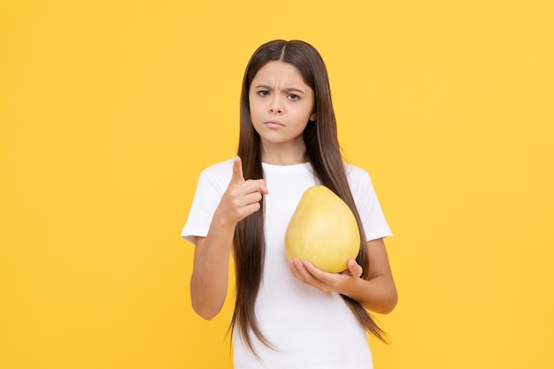 Adolescente sérieuse avec pomelo. vitamines et régimes amaigrissants. alimentation saine. santé de l'enfance. gros agrumes exotiques. pomelo frais mûr biologique naturel. vie saine. régime de fruits.