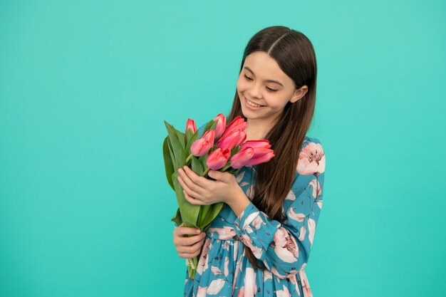 Adolescente souriante avec bouquet de printemps sur fond bleu cadeau floral