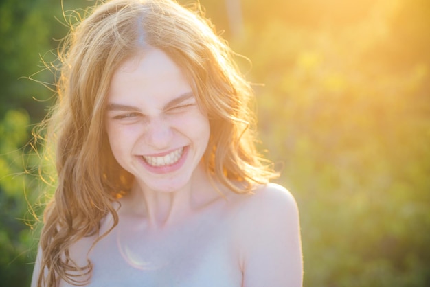 Adolescente souriante en chemisier bleu contre le vert du parc d'été printemps sourire visage de fille