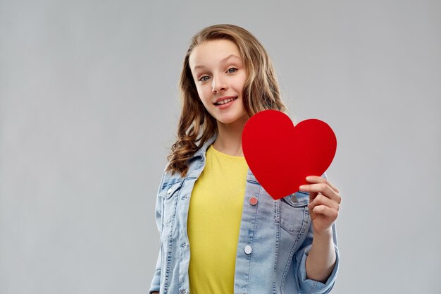Une adolescente souriante avec un cœur rouge.