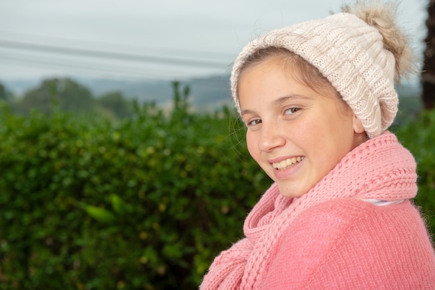 Adolescente souriante avec pull rose et chapeau d&#39;hiver