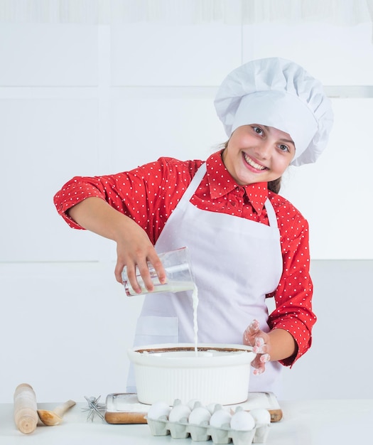 Adolescente souriante en uniforme de chef cuisine et pâtisserie
