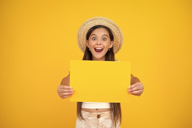 Une adolescente surprise tient un papier publicitaire vide avec un espace de copie sur fond jaune