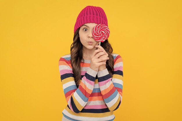 Une adolescente surprise tient une sucette sucette dame hipster enfant avec des bonbons de sucre sucette colorée