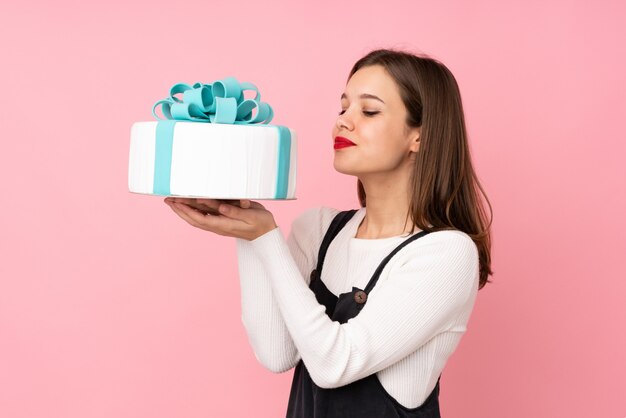 Adolescente tenant un gros gâteau rose