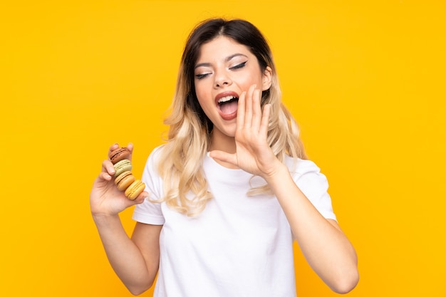 Adolescente tenant des macarons français colorés et criant