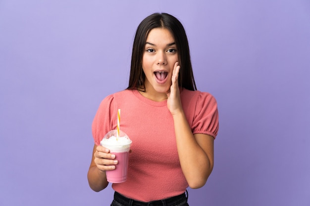 Adolescente tenant un milk-shake aux fraises avec surprise et expression faciale choquée