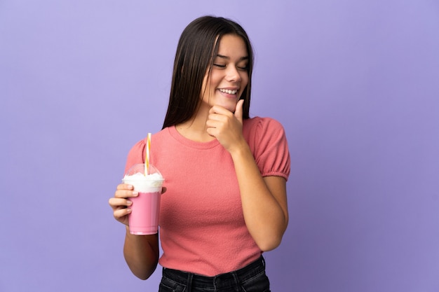 Adolescente tenant un milkshake aux fraises à la recherche sur le côté et souriant