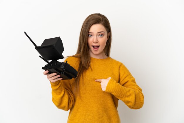 Adolescente tenant une télécommande de drone sur fond blanc isolé avec une expression faciale surprise