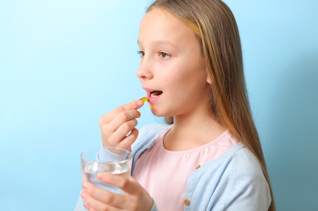 Photo une adolescente tient une capsule oméga dans ses mains sur un fond coloré