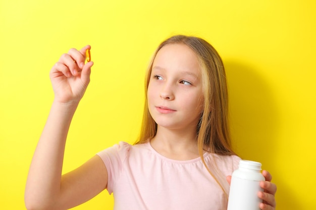 Photo une adolescente tient une capsule oméga dans ses mains sur un fond coloré