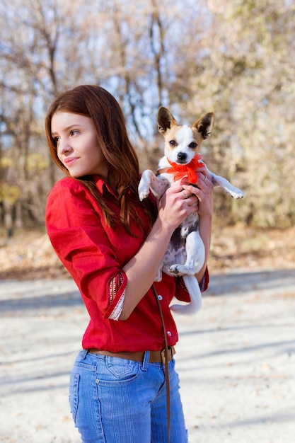 Une adolescente tient un petit terrier de jouet pour chien avec un arc rouge