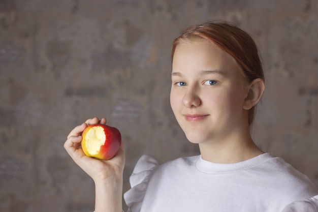 Une adolescente tient une pomme mordue