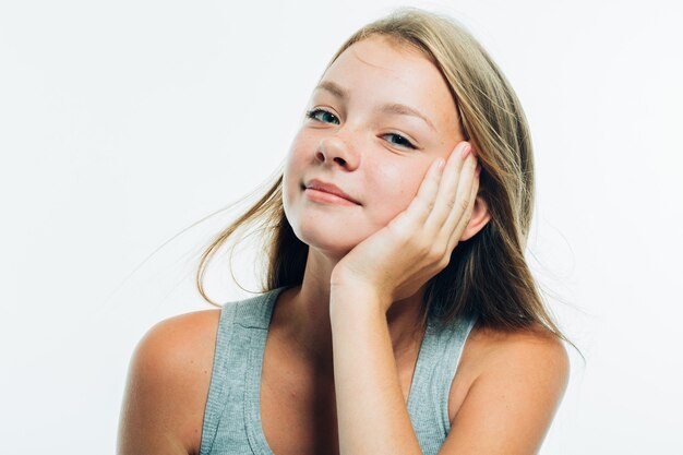 Une adolescente touche sa joue. Portrait de jeune femme au visage tacheté de rousseur. Isolé sur blanc. Prise de vue en studio.