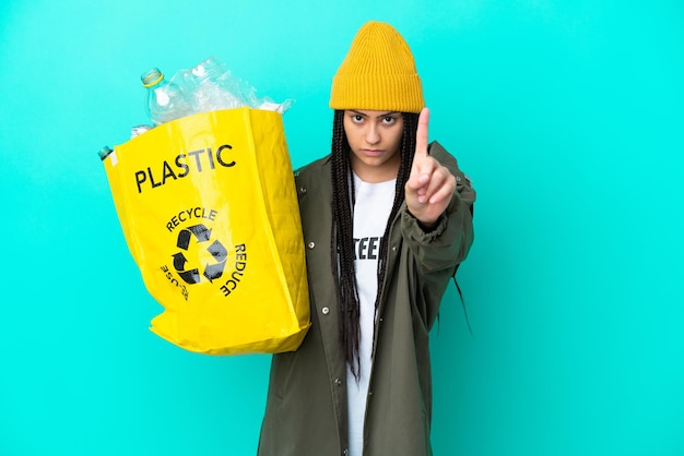 Adolescente avec des tresses tenant un sac pour recycler en comptant un avec une expression sérieuse