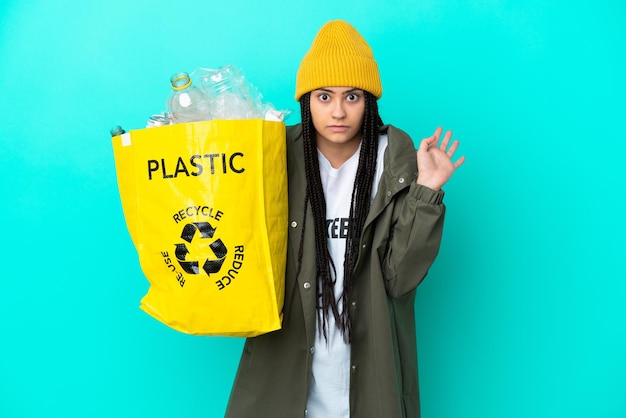 Photo adolescente avec des tresses tenant un sac à recycler en faisant un geste de doute