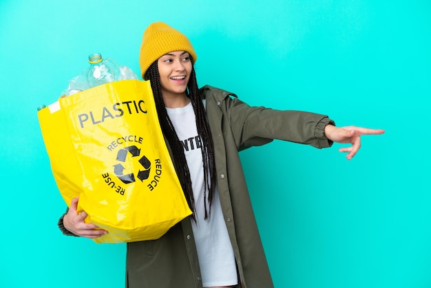 Adolescente avec des tresses tenant un sac à recycler pointant le doigt sur le côté et présentant un produit