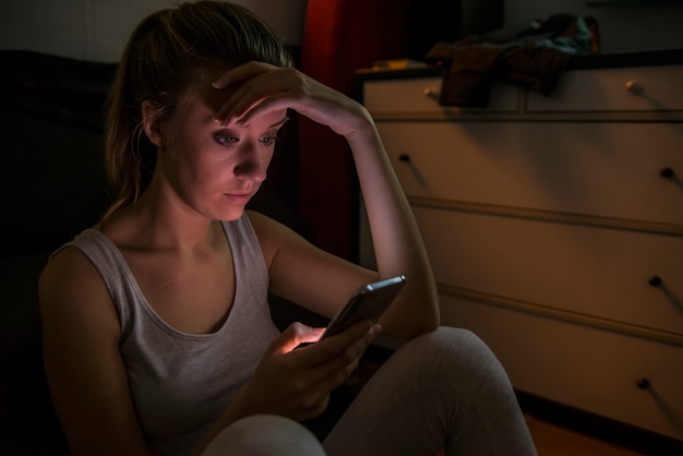 Une adolescente triste et grincheuse envoie un message sur son téléphone portable intelligent