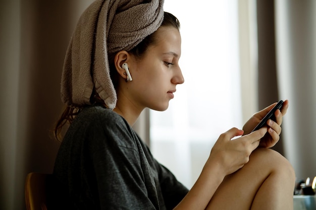 Une adolescente en turban fait de serviettes dans le salon ressemble à un smartphone