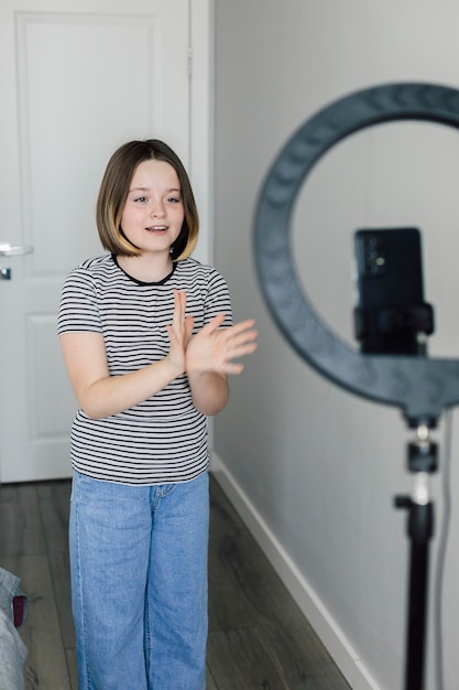 Une adolescente utilisant un téléphone portable prend un clip vidéo dansant à partager sur l'application tiktok