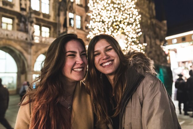 Adolescentes et amis souriant avec arbre de Noël
