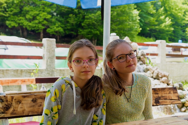 Adolescentes caucasiennes dans des verres assis à une table sur un parc d'été verdoyant.