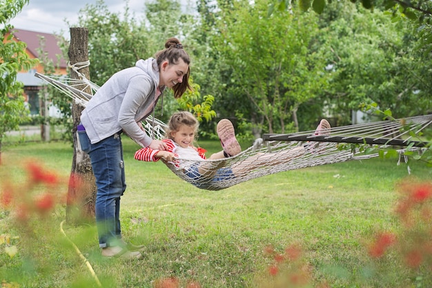 Adolescentes et enfants s'amusant dans le jardin sur un hamac