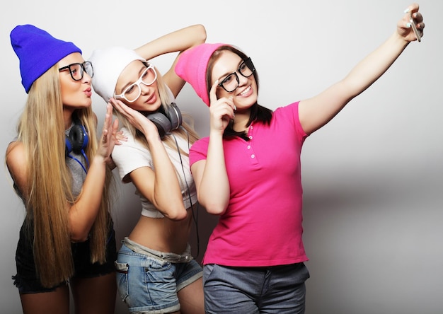 Des adolescentes heureuses avec un smartphone qui se font des selfies.