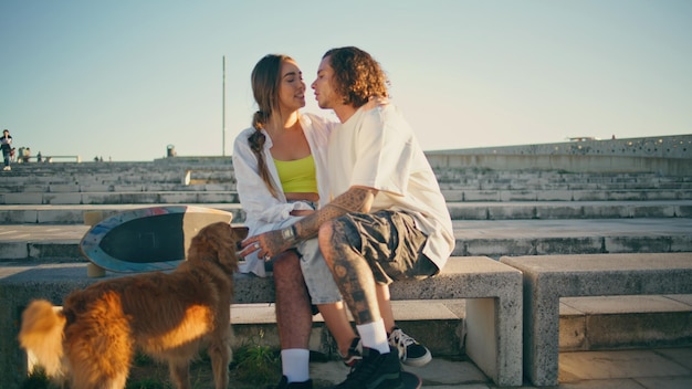 Des adolescents amoureux embrassant un banc urbain deux patineurs qui sortent dans un stade en été