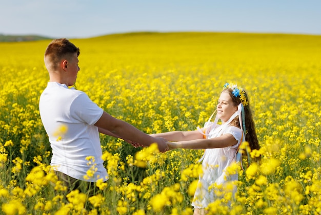 Adolescents frère et sœur avec couronne ukrainienne avec sur la tête dans le champ de colza sous le ciel bleu