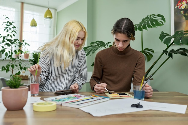 Adolescents Gars Et Fille Assis à Table Avec Des Dessins De Pinceaux De Peinture