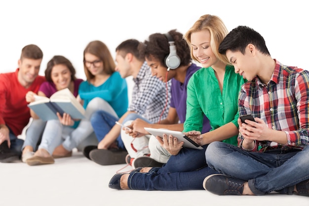 Adolescents insouciants. Groupe d'étudiants multiethniques passant du temps ensemble assis isolés sur blanc