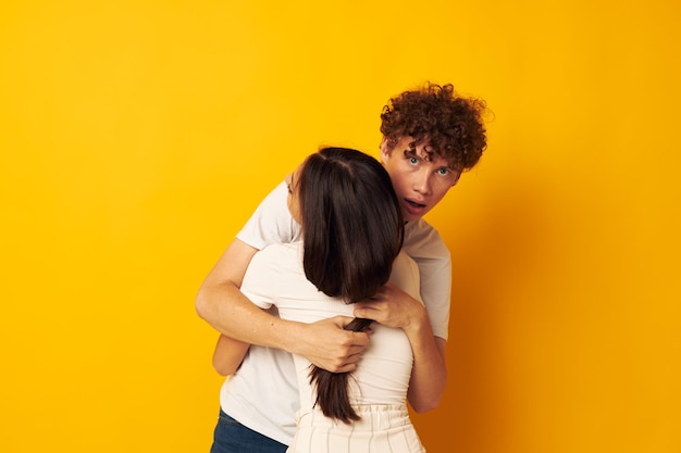 Les adolescents se serrant les uns les autres dans des t-shirts blancs sur fond jaune inchangés