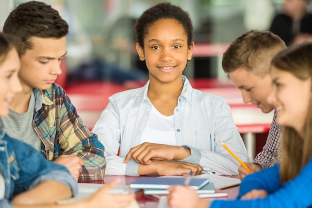 Photo les adolescents sont assis à la table et occupés avec des leçons.