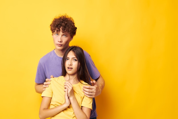 Adolescents en t-shirts colorés posant amitié amusant fond jaune inchangé