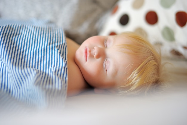 Adorable bambin garçon dormant dans un lit