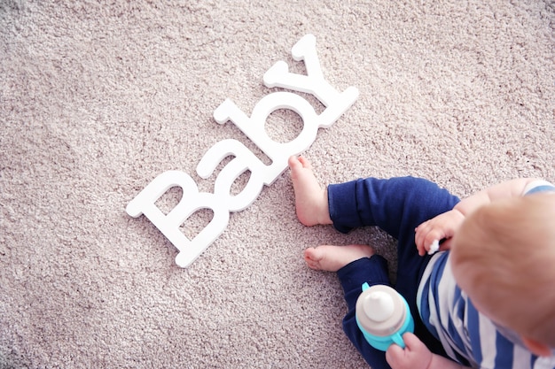 Adorable bébé assis sur un sol