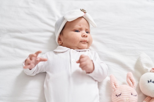 Adorable bébé hispanique allongé sur le lit dans la chambre