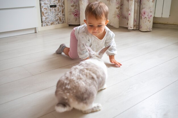 Adorable bébé jouant avec un lapin décoratif à la maison