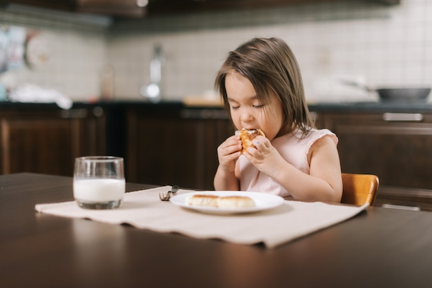 Adorable belle petite fille mange du cheesecake avec ses mains pour le déjeuner