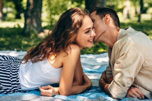 Adorable couple amoureux datant à l'extérieur du parc par une journée ensoleillée Heureux couple amoureux s'embrassant regardant avec amour ayant les yeux pleins de bonheur Date jour Temps en famille