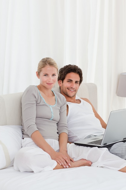 Adorable couple en regardant leur ordinateur portable sur le lit